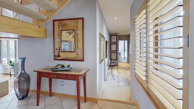 hallway featuring baseboards, light tile patterned flooring, and recessed lighting