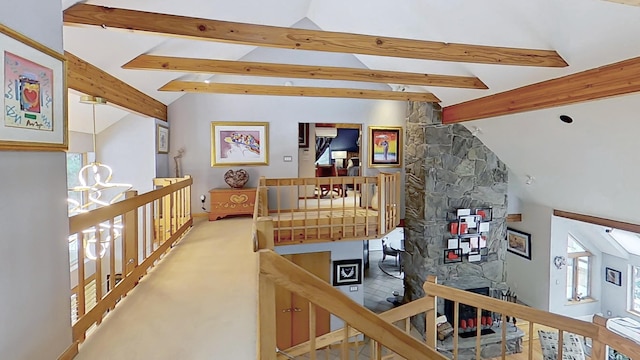 interior space featuring carpet flooring, lofted ceiling with beams, and an upstairs landing