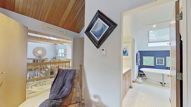 hallway with wooden ceiling, vaulted ceiling, and an upstairs landing