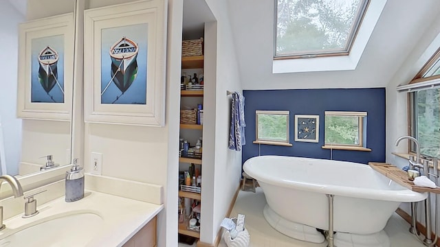 bathroom featuring vaulted ceiling with skylight, a soaking tub, vanity, and a healthy amount of sunlight