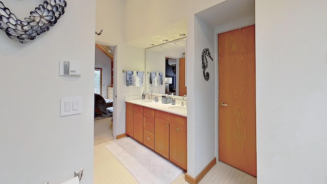 bathroom featuring baseboards, double vanity, a sink, and connected bathroom