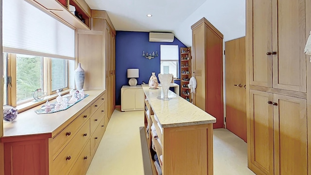 kitchen featuring light stone counters, a center island, recessed lighting, light colored carpet, and an AC wall unit