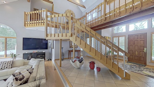 living room featuring high vaulted ceiling, stairway, and baseboards