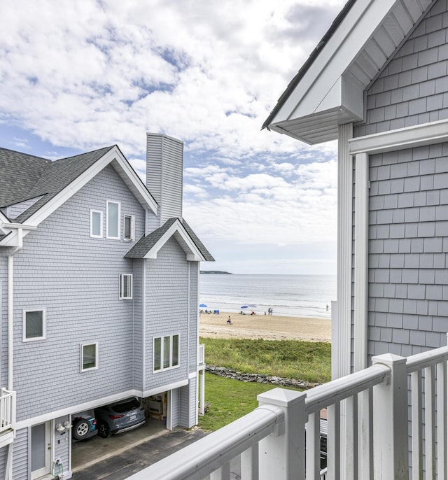 exterior space with a water view, a balcony, and a view of the beach