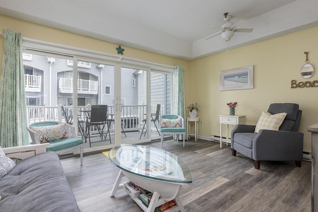 living room featuring hardwood / wood-style flooring, a baseboard heating unit, and ceiling fan