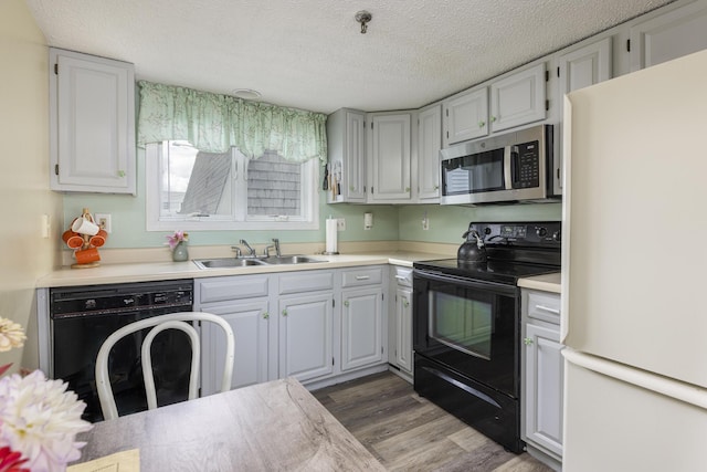 kitchen featuring dark hardwood / wood-style floors, sink, a textured ceiling, and black appliances