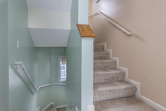 stairs with carpet floors and a textured ceiling