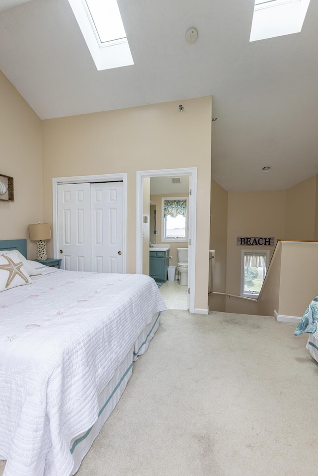 carpeted bedroom with ensuite bath, lofted ceiling with skylight, and a closet
