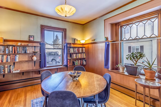 dining area with a baseboard radiator, crown molding, and light hardwood / wood-style floors