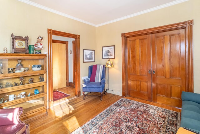 living area with hardwood / wood-style flooring and crown molding