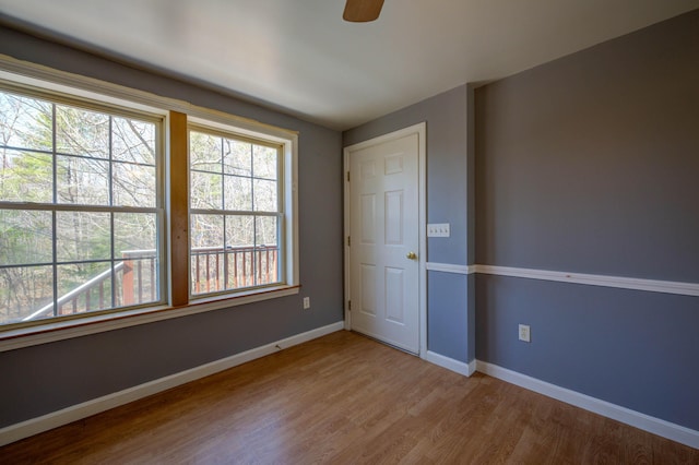 unfurnished room with a ceiling fan, wood finished floors, and baseboards