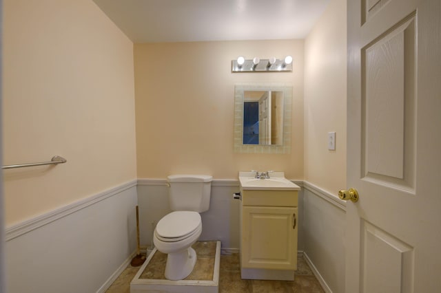 half bath featuring baseboards, toilet, and vanity