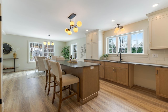 kitchen with light wood-style floors, plenty of natural light, a sink, and backsplash