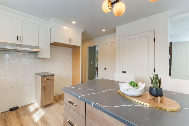 kitchen with dark countertops, light wood finished floors, tasteful backsplash, and recessed lighting