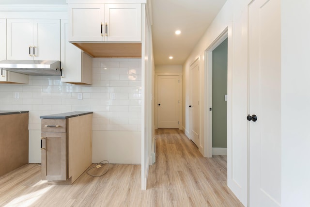 kitchen with light wood-style flooring, recessed lighting, under cabinet range hood, and tasteful backsplash