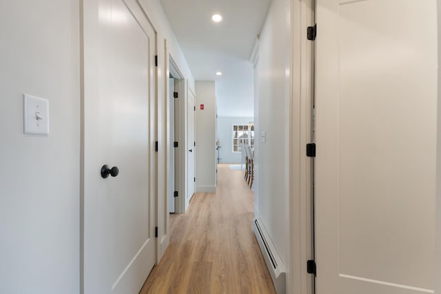 corridor with light wood-type flooring, baseboards, a baseboard heating unit, and recessed lighting