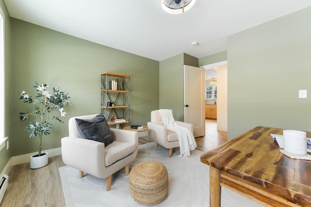 living area with a baseboard radiator, wood finished floors, and baseboards