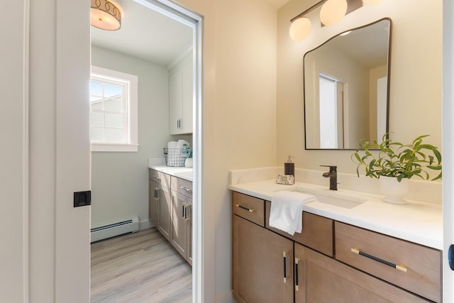 bathroom with a baseboard heating unit, wood finished floors, and vanity