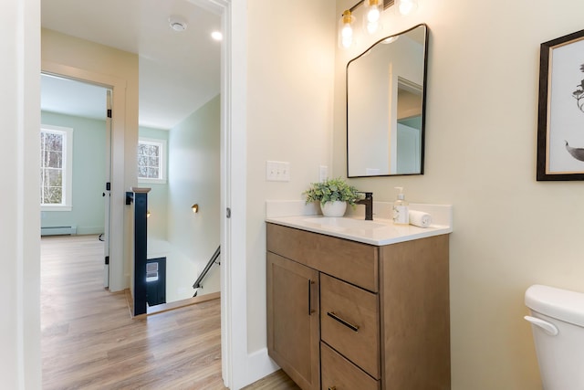 bathroom featuring toilet, baseboard heating, wood finished floors, and vanity