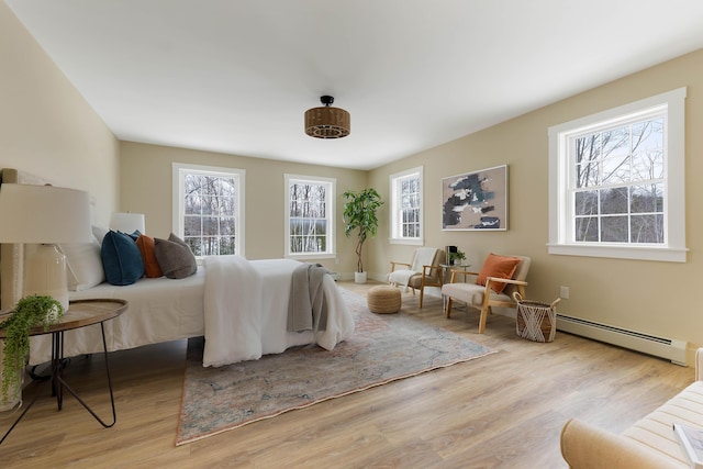 bedroom featuring multiple windows, a baseboard heating unit, and wood finished floors