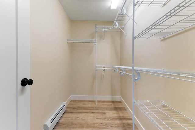 spacious closet with a baseboard heating unit and light wood-style floors