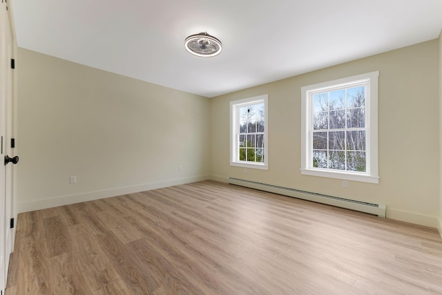 unfurnished room featuring baseboards, light wood finished floors, and baseboard heating