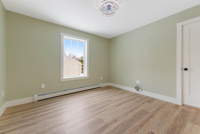 spare room with baseboard heating, wood finished floors, and baseboards