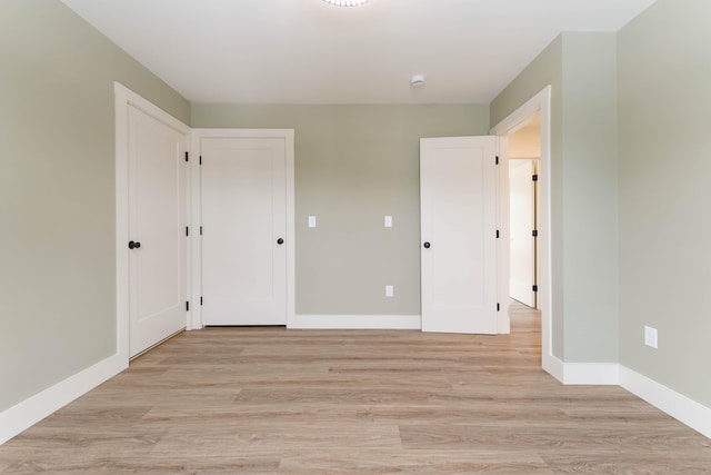 unfurnished bedroom with baseboards and light wood-style floors