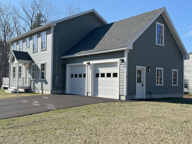 view of front of house with driveway, a front yard, a shingled roof, and a garage