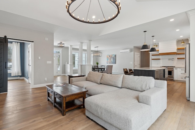 living room featuring a barn door, a notable chandelier, a baseboard heating unit, light wood-style floors, and a wall mounted AC