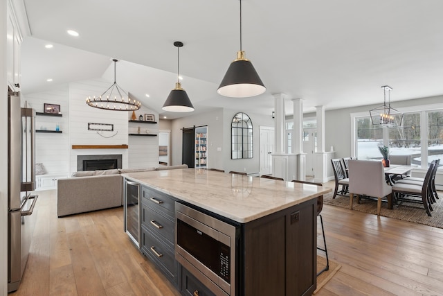 kitchen featuring vaulted ceiling, appliances with stainless steel finishes, a barn door, and light wood-style floors