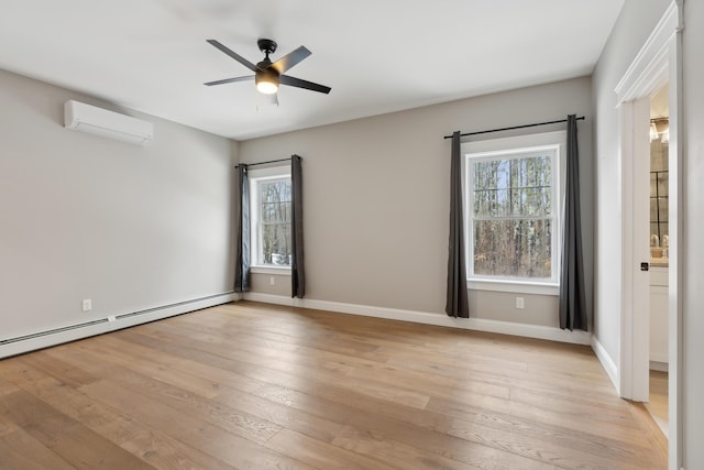 empty room featuring plenty of natural light, baseboard heating, a wall mounted air conditioner, and light wood-style flooring