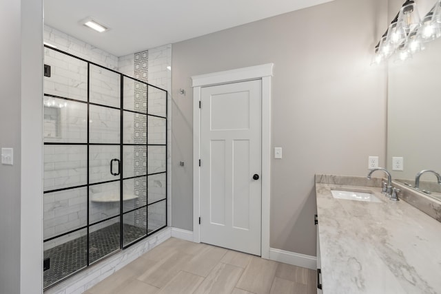 bathroom with a stall shower, vanity, and baseboards