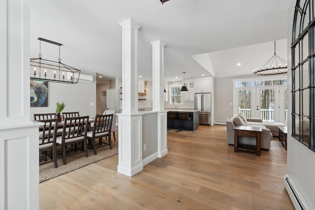 interior space with light wood finished floors, decorative columns, a baseboard radiator, an inviting chandelier, and french doors