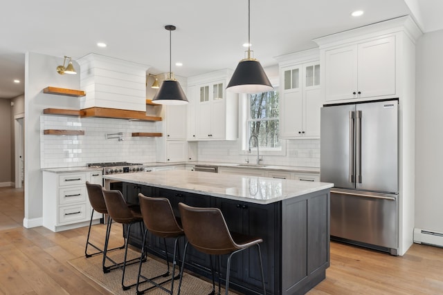 kitchen featuring high quality fridge, a kitchen island, light wood-type flooring, open shelves, and a sink