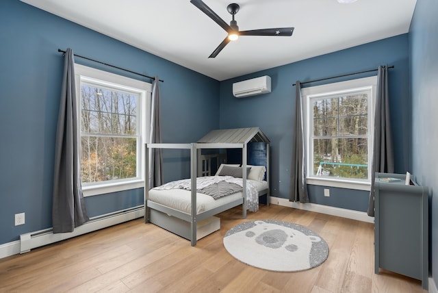 bedroom with a wall unit AC, baseboards, a baseboard heating unit, and wood finished floors