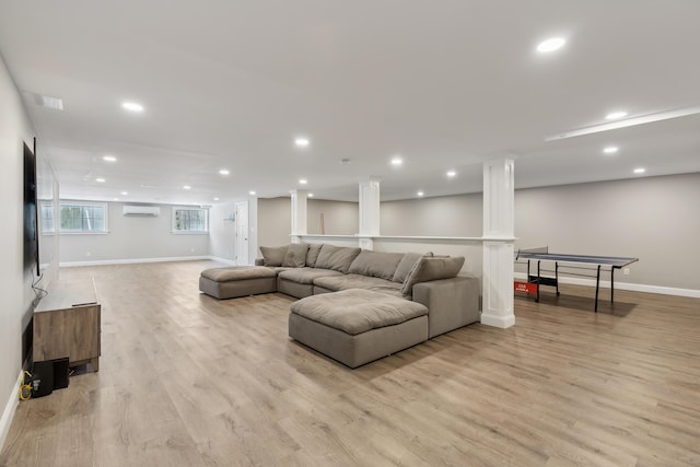 living area featuring decorative columns, baseboards, a wall unit AC, light wood-style flooring, and recessed lighting