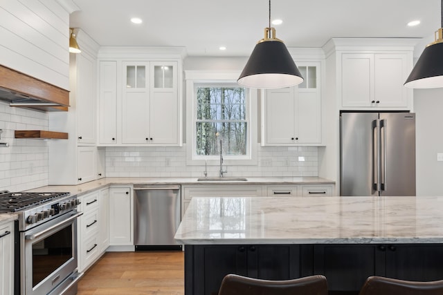 kitchen featuring glass insert cabinets, a sink, high quality appliances, and white cabinets