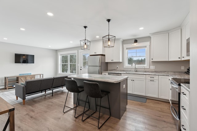 kitchen with a kitchen breakfast bar, electric stove, freestanding refrigerator, a center island, and light wood finished floors