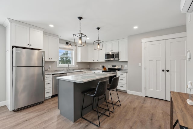 kitchen with appliances with stainless steel finishes, white cabinets, and light wood-style floors