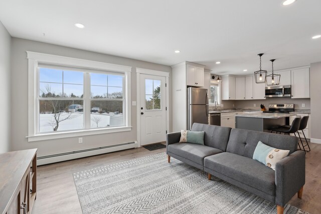 living room featuring a baseboard heating unit, light wood-style flooring, and recessed lighting