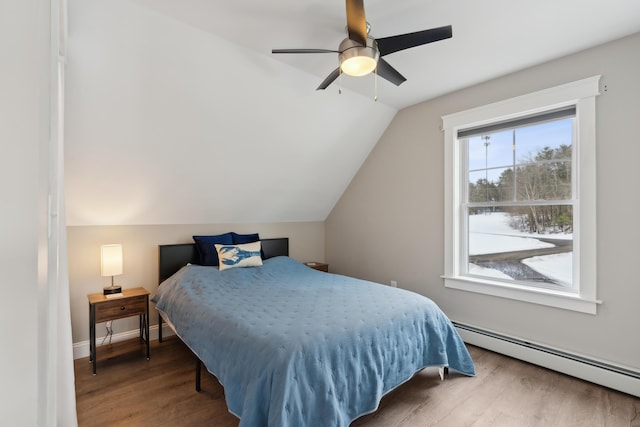 bedroom with lofted ceiling, baseboard heating, ceiling fan, wood finished floors, and baseboards