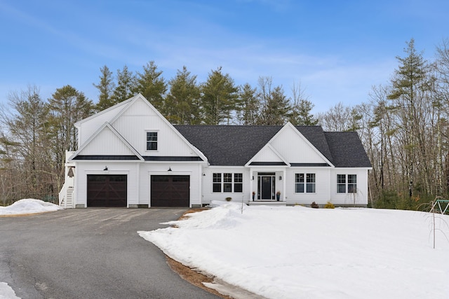 modern farmhouse featuring a garage, driveway, and a shingled roof