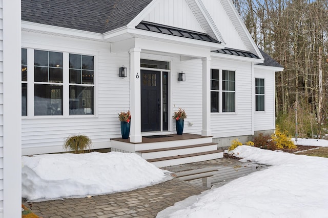 snow covered property entrance featuring a standing seam roof, metal roof, and roof with shingles