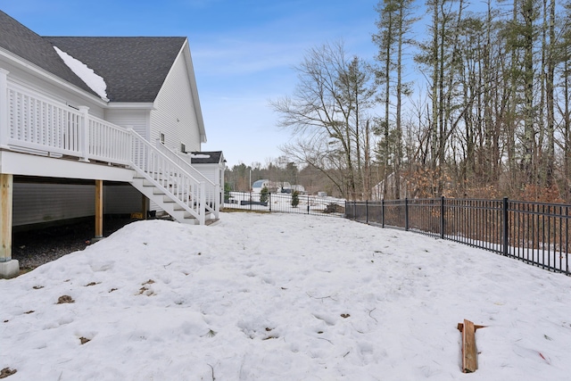 snowy yard featuring fence private yard, stairway, and a deck