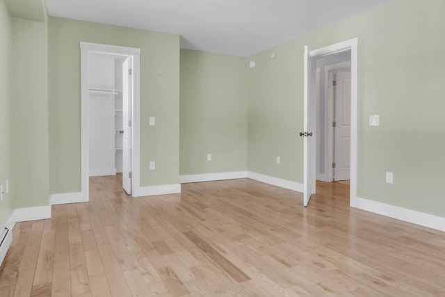 unfurnished room featuring baseboard heating and light wood-type flooring