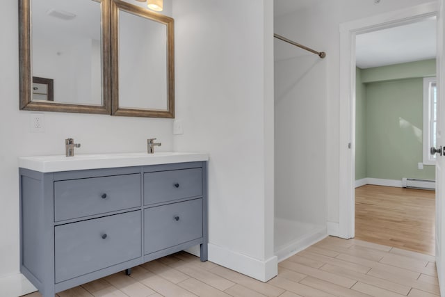 bathroom with hardwood / wood-style flooring, vanity, walk in shower, and baseboard heating