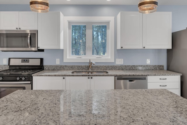 kitchen featuring sink, stainless steel appliances, white cabinetry, and light stone counters