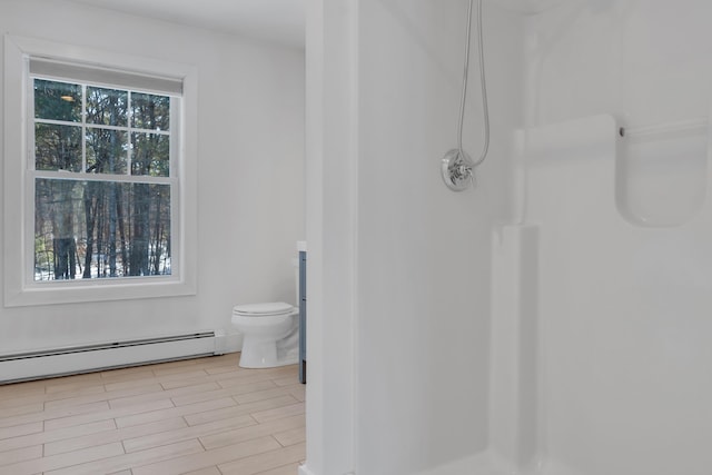 bathroom featuring a baseboard radiator, toilet, walk in shower, and a wealth of natural light