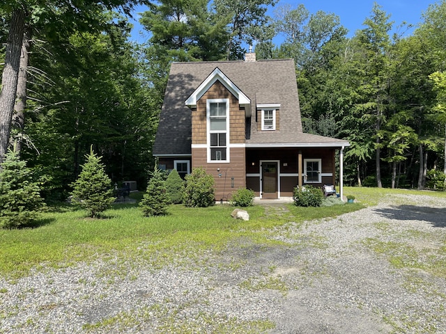 view of front of house with driveway, a shingled roof, a chimney, a porch, and a front lawn